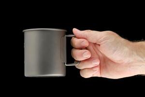Titanium cup in hand on black photo