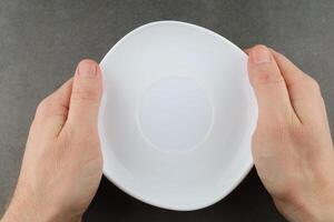 Hands hold empty white plate. Top view. photo