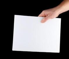 A hand holds a blank sheet of paper. photo