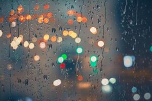 raindrops on the window and multi colored street lights at night background photo