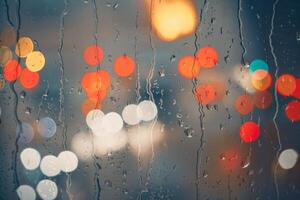 raindrops on the window and multi colored street lights at night background photo