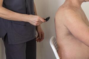 Shot of the female doctor in uniform against the white wall examining mid age male patient. Healthcare photo