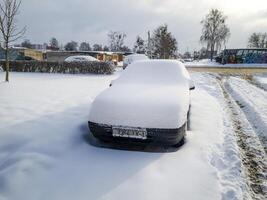 Landscape shot of the street on the winter day. Car covered in the snow. Season photo