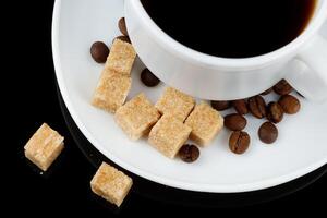 Coffee in a cup and a piece of brown sugar. Coffee drink and coffee beans with sugar. photo
