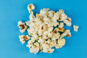 A pile of popcorn on a blue background. heap of popcorn photo