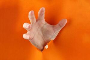 Hand through a hole in an orange cardboard photo