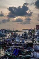 Jepara, Central Java, April 7, 2024 - Jepara fishing boats parked in a crowded harbor against the backdrop of the evening sky with empty space for advertising photo