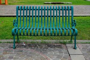 a green park bench and a meadow behind the armchair. photo