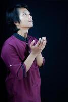 side view of a man raising his hands in prayer on a black background. photo