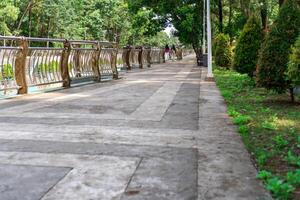 Road in Serpong City Park, South Tangerang with trees and river safety fence. photo