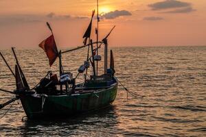 fishing boats on the sea against an orange sky at night with empty space for photocopies. photo