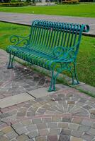 a green park bench and a meadow behind the armchair. photo