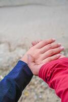 the hands of a couple holding hands against the background of beach sand. photo