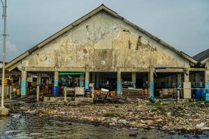 Jepara, Central Java, April 7, 2024 - The building where the fish auction is located is starting to erode with age, with rubbish strewn along the side of the building. photo