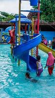 jepara, central Java, abril 14, 2024 - nadando piscina paseos para niños con vistoso diapositivas foto