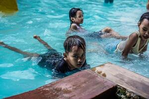jepara, central Java, abril 14, 2024 - niños jugando en el nadando piscina durante colegio vacaciones. foto