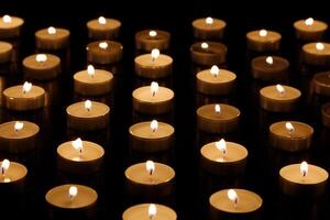 Many burning candles with shallow depth of field. Many small candles on a black background. photo