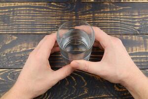 un vaso de agua en manos en el mesa foto