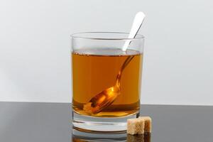 A glass of tea with pieces of sugar photo