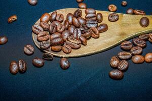 negro café frijoles son visto cerca arriba con un de madera cuchara en un negro paño. foto