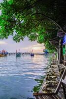 seen close up from a folding chair by the sea with a background of fishing boats leaning on the pier isolated against the evening sky. photo