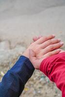 the hands of a couple holding hands against the background of beach sand. photo