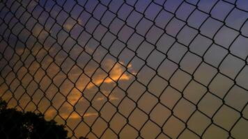 shot of the iron net fence against the background of an orange sky in the afternoon. photo