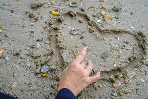 dibujar un firmar de amor en el arena de el línea costera. foto