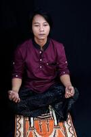 front view of a man praying on a prayer mat with a black background. photo