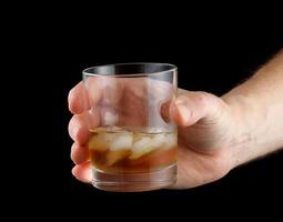 Whiskey with ice in a glass in hand. photo