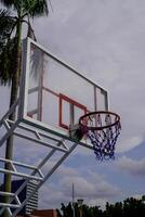 Close-up view of a basketball basket against a cloudy sky background. photo