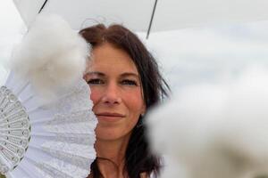 un mujer con un blanco ventilador y paraguas y un nube en el primer plano foto