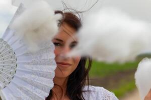 un mujer con un blanco ventilador y paraguas y un nube en el primer plano foto