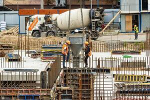 RUSSIA, KALUGA - AUGUST 15, 2022 Workers assembling the frame of a building from rebar. photo