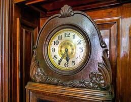 Wooden antique clock, decorated with patterns with Arabic numerals. photo