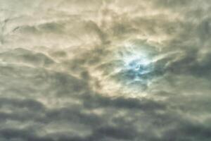 Partial solar eclipse passing behind the clouds. photo