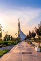 uzbekistán, Tashkent - septiembre 15, 2023 Monumento de independencia en el formar de un estela con un humo pájaro en un crepúsculo con dramático clidos en el nuevo Uzbekistán parque. foto