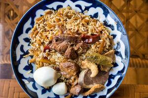 Top view of a plate with Uzbek oriental pilaf with pieces of lamb, horse meat, quail rice and chicken egg. Central Asian cuisine. photo