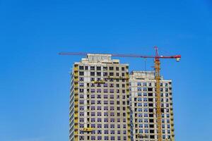 A crane building a skyscraper against a blue sky. photo