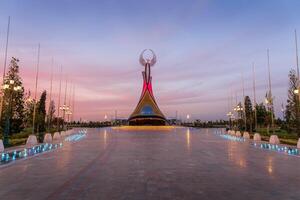 uzbekistán, Tashkent - septiembre 15, 2023 Monumento de independencia en el formar de un estela con un humo pájaro en un crepúsculo con dramático clidos en el nuevo Uzbekistán parque. foto