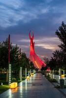 UZBEKISTAN, TASHKENT - SEPTEMBER 15, 2023 Illuminated monument of independence in the form of a stele with a Humo bird in the New Uzbekistan park at nighttime in autumn. photo
