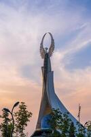 UZBEKISTAN, TASHKENT - SEPTEMBER 15, 2023 Monument of Independence in the form of a stele with a Humo bird on a twilight with dramatic cliods in the New Uzbekistan park. photo