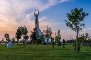 uzbekistán, Tashkent - septiembre 15, 2023 Monumento de independencia en el formar de un estela con un humo pájaro en un crepúsculo con dramático clidos en el nuevo Uzbekistán parque. foto