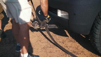 un hombre en el Desierto manos un remolcar cuerda sobre un coche. video