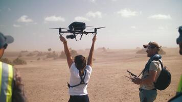 A girl catches a quadcopter with a camera in the air on the set of a movie video