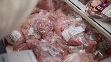 riga, Lettonia -28 aprile 2024. nel un' supermercato, un' mano seleziona carne, la scelta a partire dal un' varietà di carne nel borse. con attenzione, il mano scelte qualità carne nel borse, garantendo freschezza e qualità.editoriale video
