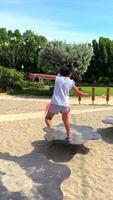 Playground for kids in a park, busy with excited and joyful children having fun and playing on merry-go-round, slide, playhouse and swing and running around. video