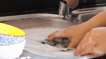 cerca arriba de mano haciendo plato Lavado en el moderno cocina hundir. alto calidad 4k imágenes video