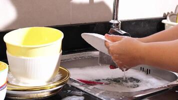 vicino su di mano fare piatto lavaggio nel il moderno cucina lavello. alto qualità 4k metraggio video