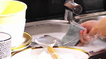 vicino su di mano fare piatto lavaggio nel il moderno cucina lavello. alto qualità 4k metraggio video
